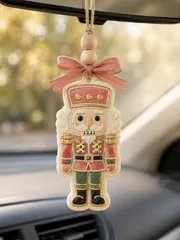Handmade Christmas nutcracker freshie car air freshener made from scented aroma beads, shaped like a classic red and gold nutcracker soldier, hanging from a car rearview mirror.