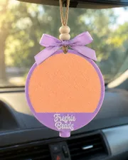 Round personalized car freshie with a custom name in cursive script, a handmade scented aroma bead air freshener for hanging on a car mirror.