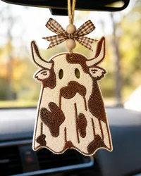 Handmade ghost cow car freshie, a cute cow-shaped scented air freshener covered in a white Halloween ghost sheet, hanging in a car for cow lovers and western fall decor.