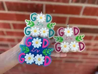 Handmade scented aroma bead car freshie air freshener reading God is Good with white daisies forming the O letters and green leaf sprigs, shown in three colorways.