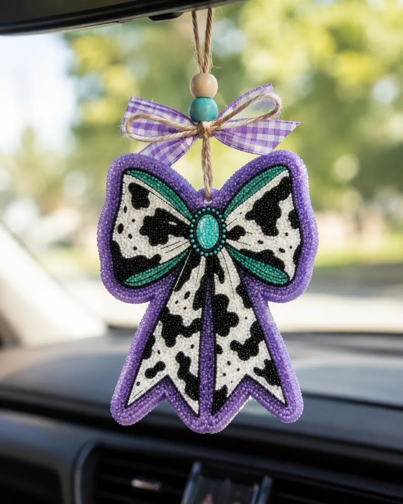 Retro western cow print bow-shaped car freshie air freshener made of scented aroma beads, hanging from a rearview mirror with a cowgirl country style.